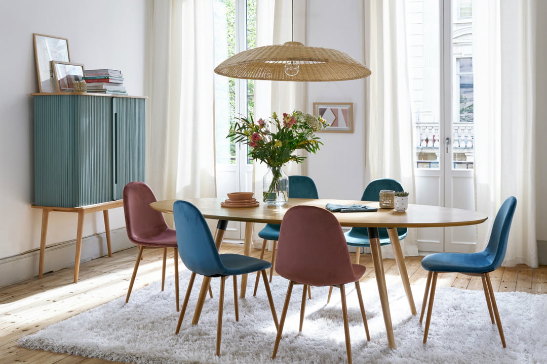 Salle à manger décorée de façon scandicraft avec des murs blancs, du mobilier en bois et du mobilier aux couleurs bleu et bordeau