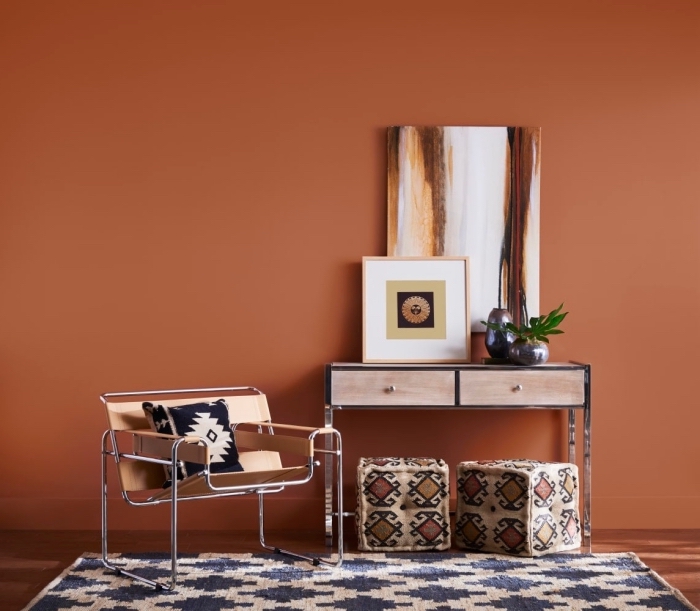 Mur de couleur terracotta avec du mobilier en bois sombre et un tapis au motif bleu et blanc