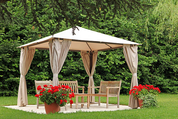 Tonnelle blanche dans un jardin avec pots de fleurs et bancs en bois